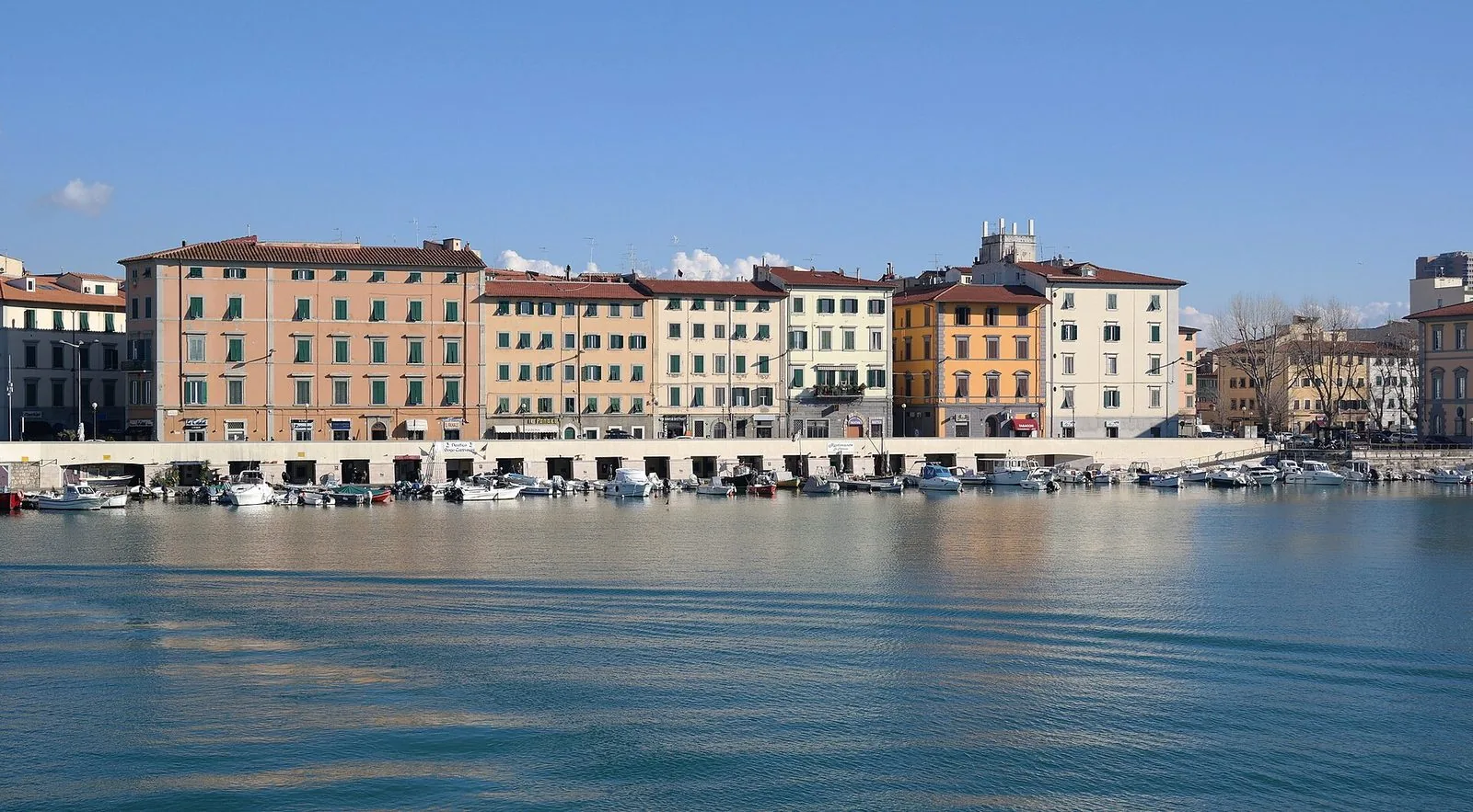 Gli Scali Novi Lena a Livorno visti dall’acqua della Darsena, con una fila di palazzi colorati e piccole barche ormeggiate lungo la banchina