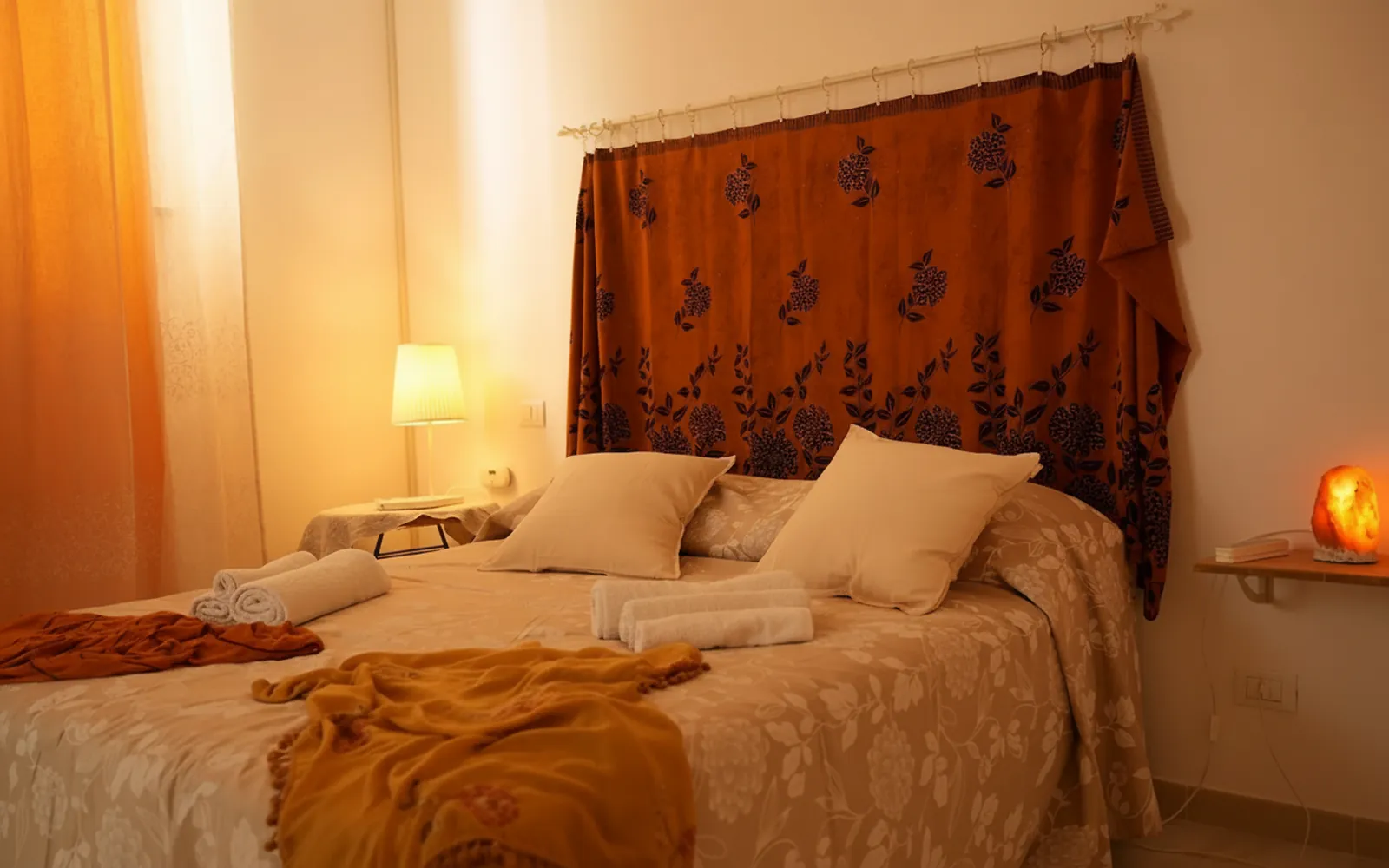 La camera matrimoniale con le abat-jour accese e il tessuto sopra la testiera